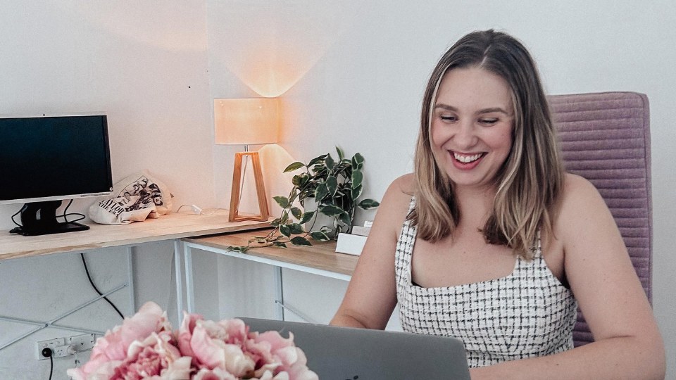 Ashleigh Kay smiling at her laptop in her home office