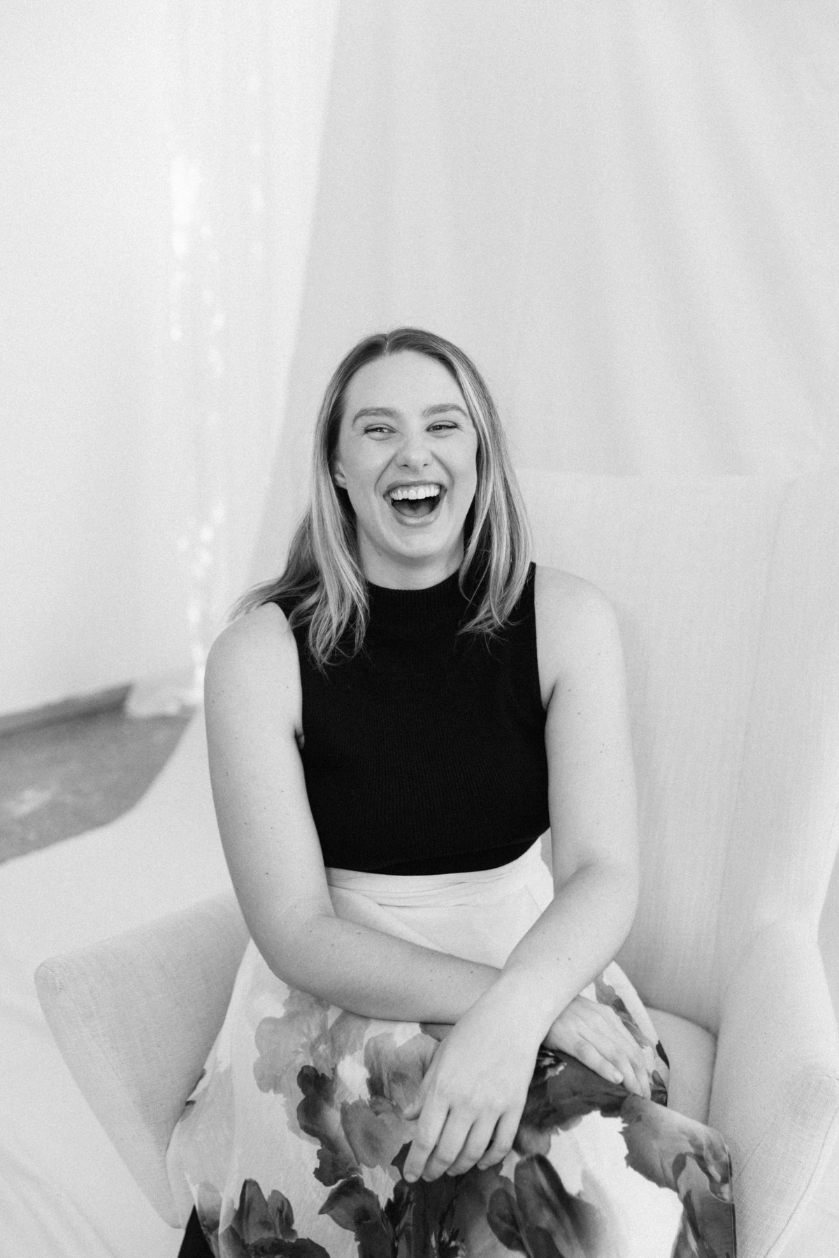 Ashleigh Kay, founder of AKEA, laughing in a cream armchair